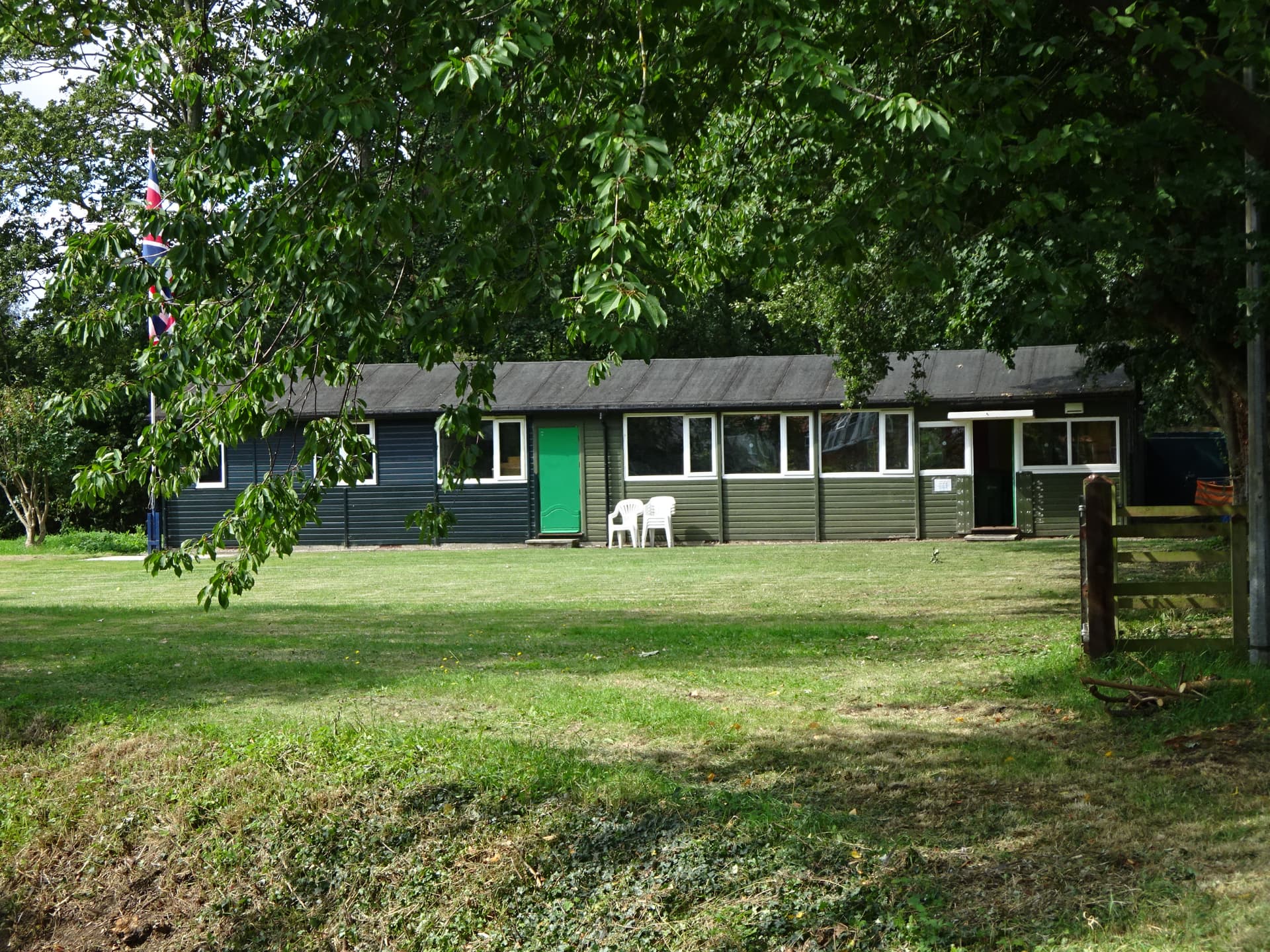 View across the field towards the scout hut, framed by trees